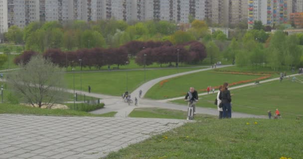 Miasto dzień Opole widok ludzi mieszkalnej Biding rowerów przez alejki w parku stoi na trawnikach i patrząc na wiosnę krajobraz Green Hills drzew — Wideo stockowe