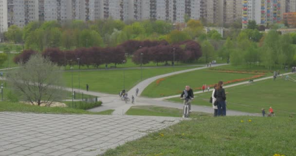 Stadt Tag Opole Blick auf Wohngebiet Menschen, die Fahrräder durch Gassen im Park stehen auf einer Wiese und Blick auf Frühlingslandschaft grüne Hügel Bäume — Stockvideo