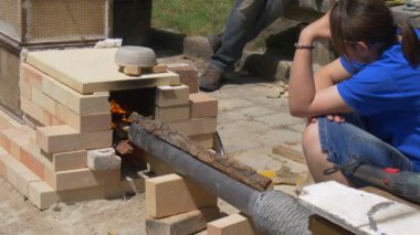 Genç kız oturur bir tezgah ve yangın bakar