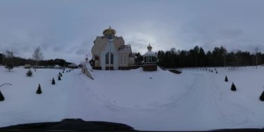 360 vr Video 360 Degrees. Man is Filming Wintry View of Orthodox Church of the Holy Elijah in Slavutich City, Ukraine. Cameraman is Walking by Road, Which Leads to the Building, Alley Decorated With Evergreen Trees Planted Along the Way. Silhouettes