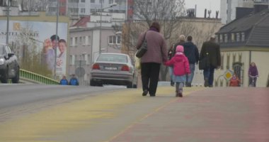 Opole, Polonya - 12 Nisan 2016: Yayalar Sarı Yol 'dan geçiyor. Bisikletçiler Kırmızı Yol 'un yanından geçiyor. Arabalar otobanda gider. Yayalar kalın bir kış elbisesi giyiyorlardı. Bir Şehir Günü Kutlamasında Ana Şehir Stadyumu 'nda çekilmiş bir video.