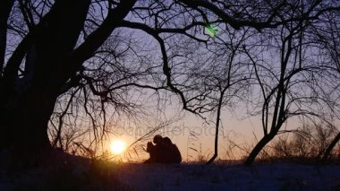 Günbatımı ve yerde oturan turist ile kış manzarası