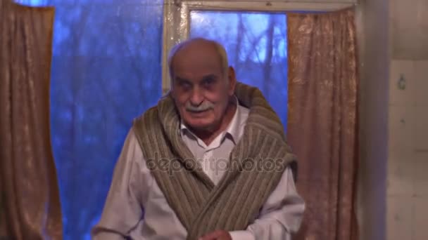 Bělovlasý muž sedí poblíž okno na domácí ctihodný dědeček se usmíval se šťastný aby vidět jeho Návštěvníci starý muž v bílé košili Family Holiday pospolitosti — Stock video