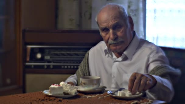 Vecchio sta mescolando zucchero in un tè ha prima colazione seduta a tavola in accogliente salotto Vintage Radiogramma in dietro freddo inverno giorno a casa nostalgia — Video Stock