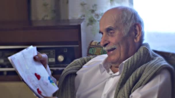 Kıdemli biri Reminiscing büyükbabam arıyor, çocuğun çizimleri bekleyen için onun torunları ziyaret aile toplandı birlikte sıcak Cosy Oda mutlu yaşlı adam — Stok video