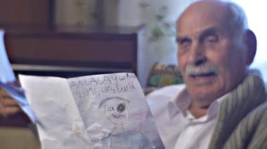 Yaşlı adam bir hediye gelen çocuklar Holding çizimleri almak için sevindim ve gurur, onun mutlu Birleşik aile Dede değil rahat odasında yalnızdır gösterir