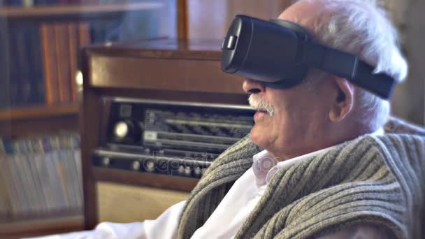 兴奋的祖父在 vr 眼镜是看视频，然后把耳机关闭高级人和次旧书技术链接和现代电影 — 图库视频影像