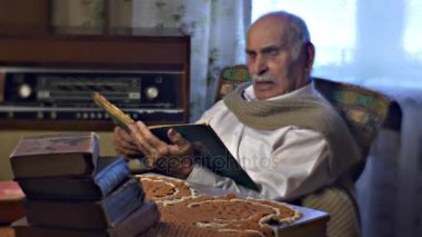 Adam eski kitap yüksek sesle Absorbedly ziyaret edenler okuma Vintage oturma odasında yaşlanma vardır dinleme anıları bir yaşlı adam aile değerleri büyükbaba 80 yıl eski