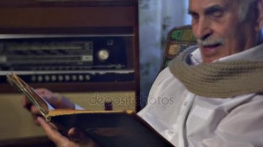 Eski kitap okuma ve bir yaşlı adam aile anıları kağıtları Leafing fotoğrafları mutluluk arayan adam yaşlanma büyükbaba değerleri 80 yıl eski evde