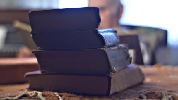 Купа книг на столі старіння людини на тлі любить читати доктор вчений дивиться через книгу працює вдома спогади старого професора — стокове відео