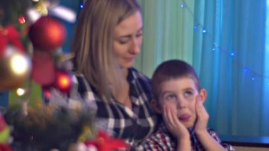 Anne oturan ile oğlu olan ekşitmeden mavi ışık süslemeleri onların oda mutlu aile kutluyor Noel tatil kadın gülümsüyor birlikte evde olduğunu