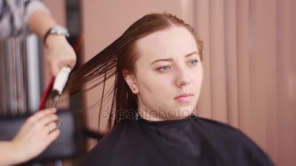 Peluquería seca un cabello húmedo de un cliente — Vídeo de stock