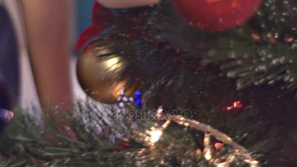 Die Hände der Menschen schmücken die Tanne Familie feiert Weihnachten grüne Nadeln leuchtet leuchtende Kugeln und Spielzeug aus Stoff Silvesterbaum zu Hause — Stockvideo