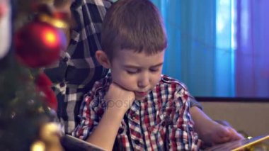 Anne oğlunu sıcak Cosy Oda Noel arifesi mavi ışık süslemeleri ile oda mutlu aile kutluyor tatil kadın gülümsüyor beraber evde okuma