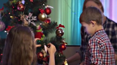 Aile evdeki Noel ağacını süslüyor.