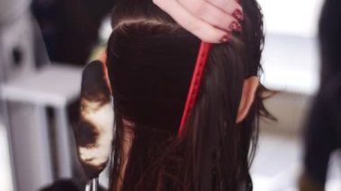Spa salonunda kadın müşterinin saçını tarayan kuaför.
