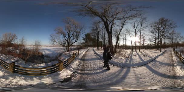 360Vr Video Il turista si guarda intorno ai margini della città Luoghi di interesse paesaggistico invernale nel parco cittadino o nel villaggio forestale Giorno freddo soleggiato L'uomo cammina lontano dalla strada innevata — Video Stock
