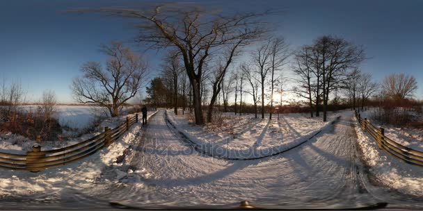 360Vr Video Backpacker camina lejos por el borde nevado del camino de la ciudad o de la aldea Paisaje rural del invierno Día soleado frío Vacaciones de tiro de la hora azul — Vídeos de Stock