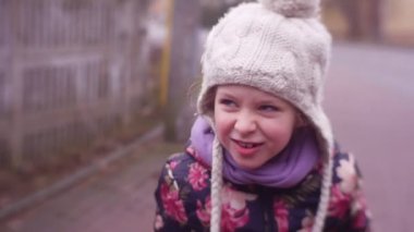 Mutlu küçük kız soğuk sonbaharda ya da kış gününde dışarıda eğleniyor.