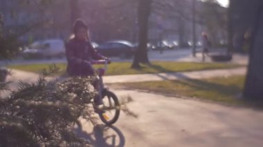 Küçük kız soğuk sonbahar ya da kış gününde bisiklet sürüyor.