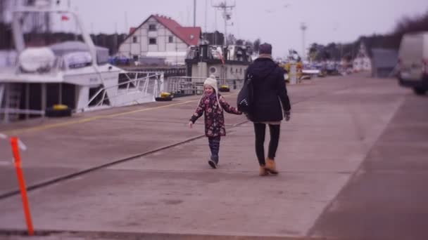 Длинноволосая девушка следует за мамой в городской порт — стоковое видео