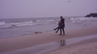 Mother and daughter walking on sea coast in cold weather