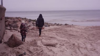 Mother and daughter spending time on sea coast in cold weather