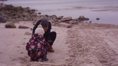 Mother and daughter spending time on sea coast in cold weather