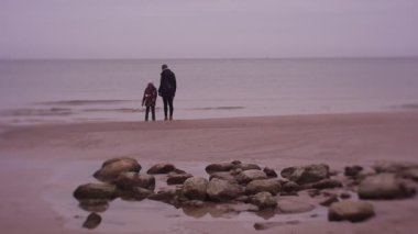 Mother and daughter spending time on sea coast in cold weather