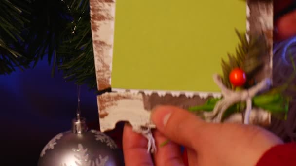 Erkek el koymak sırayla şenlikli bir el yapımı bir fotoğraf çerçevesi parlak cesaret ile dekore edilmiş Noel köknar ağacı altından cep — Stok video