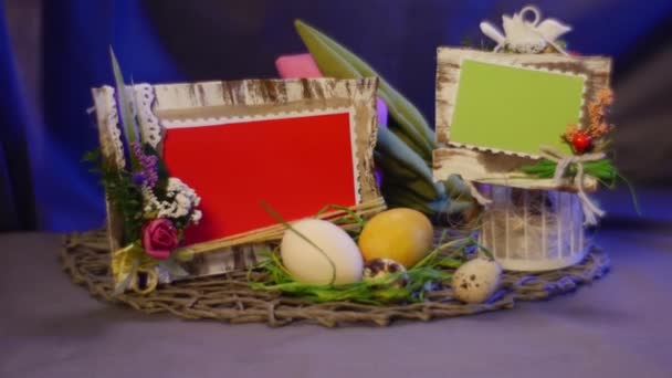 Een Pasen samenstelling van kip en kwarteleitjes, Rosy Tylips, een ingesteld van dia kaarten, een fotolijst en een vak Pasen Decor ei is gelegd op de tafel — Stockvideo