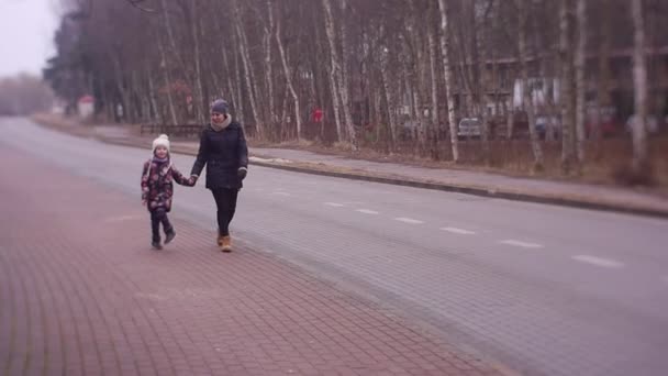 Meisje vrolijk springt omhoog tijdens lopen met de moeder — Stockvideo