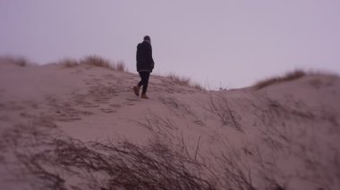 Woman walking on sea coast in cold weather