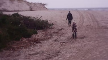 Mother and daughter spending time on sea coast in cold weather