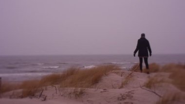 Woman walking on sea coast in cold weather