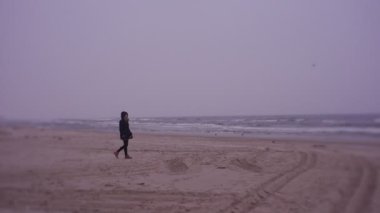 Woman walking on sea coast in cold weather