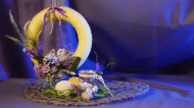 Opole, Poland - Feb 18 2017: Beautiful Yellow Fabulous Field Flowers on an Easter Ring, Hanging Over Traditional Hen and Quail Eggs on a Round Table, With a Violet Background Behind It, Being Shot With a Steadicam Camera