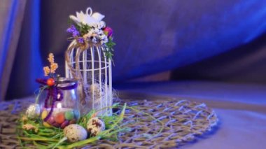 Opole, Poland - Feb 19 2017: Wonderful Composition From Easter Hen and Quail Eggs, Easter Decor Egg Box With a Red Photo Frame, a Nice Bottle With a Candle, a Top Egg Cage, Installed Near It, on a Round Table, With a Violet Background Behind It,