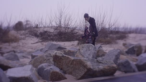 Vrouw leidt een gesprek met een kleine dochter tijdens wandeling op een strand — Stockvideo