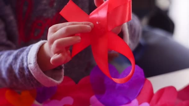 Child Knits a Bow From a Red Fabric Ribbon — Stock Video