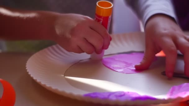 Criança esfrega uma cola em um coração de papel rosa — Vídeo de Stock