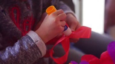 Çocuk bir kırmızı kumaş yay-düğüm üzerinde bir tutkal smear