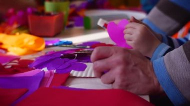 Man Helps the Child to Create Beautiful Decorations For a House. Decor Elements Lie on a Table Before Visitors of a Master Class. People Have Gathered at One Table in a City Library on the Occasion