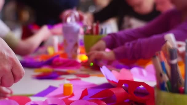 Родители и их дети делают хорошие сердца от цветной бумаги, чтобы придерживать их до белых круглых пластиковых бланков, чтобы отпраздновать День Святого Валентина в медленном движении — стоковое видео