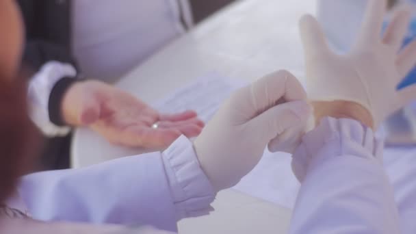 Доктор надевает белые резиновые перчатки на руки — стоковое видео