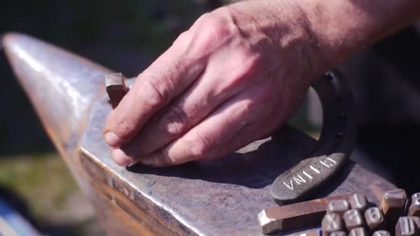 Een volwassen Man gebruikt hamer voor gravure creatie op ijzer — Stockvideo