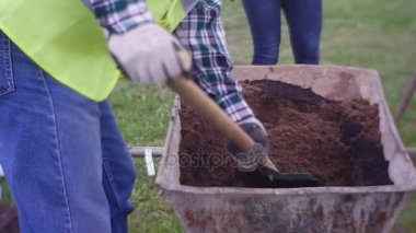 Yetişkin adam tarafından büyük bir kürek gübre ile yumuşak bir yere kaşık toz