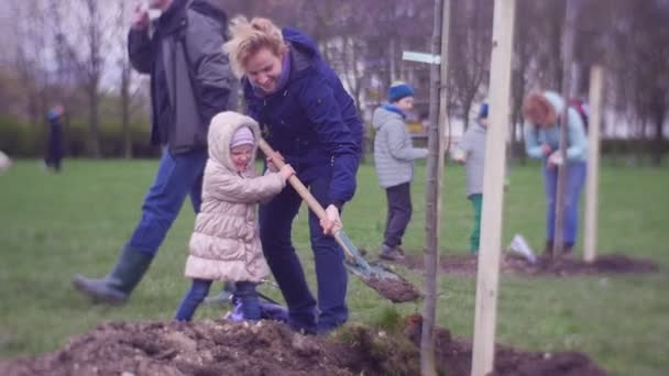 Молодая семья занялась посадкой зеленых деревьев — стоковое видео
