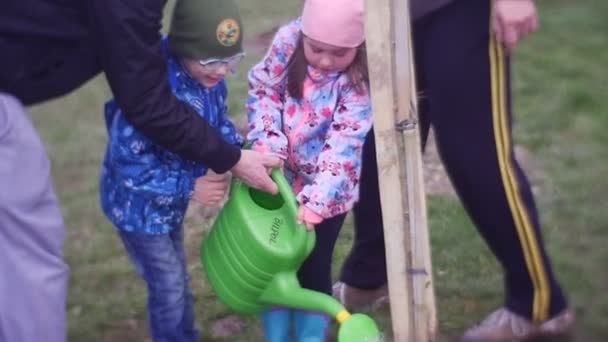 Padre attento aiuta la figlia ad innaffiare un albero — Video Stock