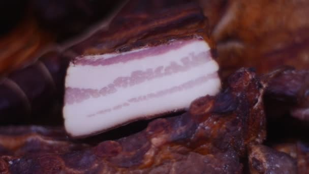 Duże kawałki mięsa wieprzowego wędzone leżą na stole, drewniane — Wideo stockowe